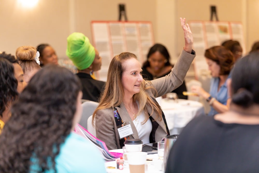 woman-raising-hand-asking-question-diverse-crowd-event