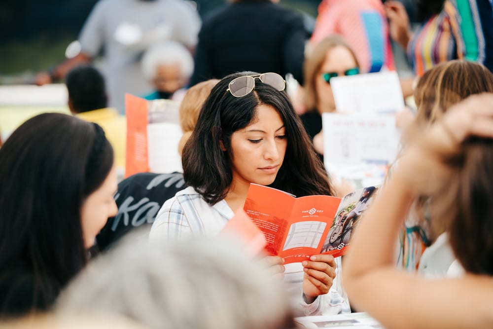 woman-reading-brochure-outdoor-group-gathering