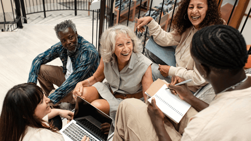 A group of changemakers sit and laugh together on a staircase