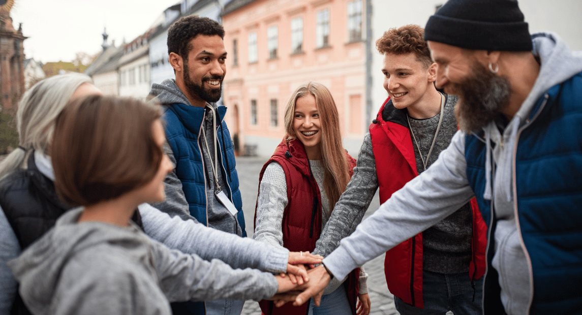 Group of people with all hands together for a team cheer