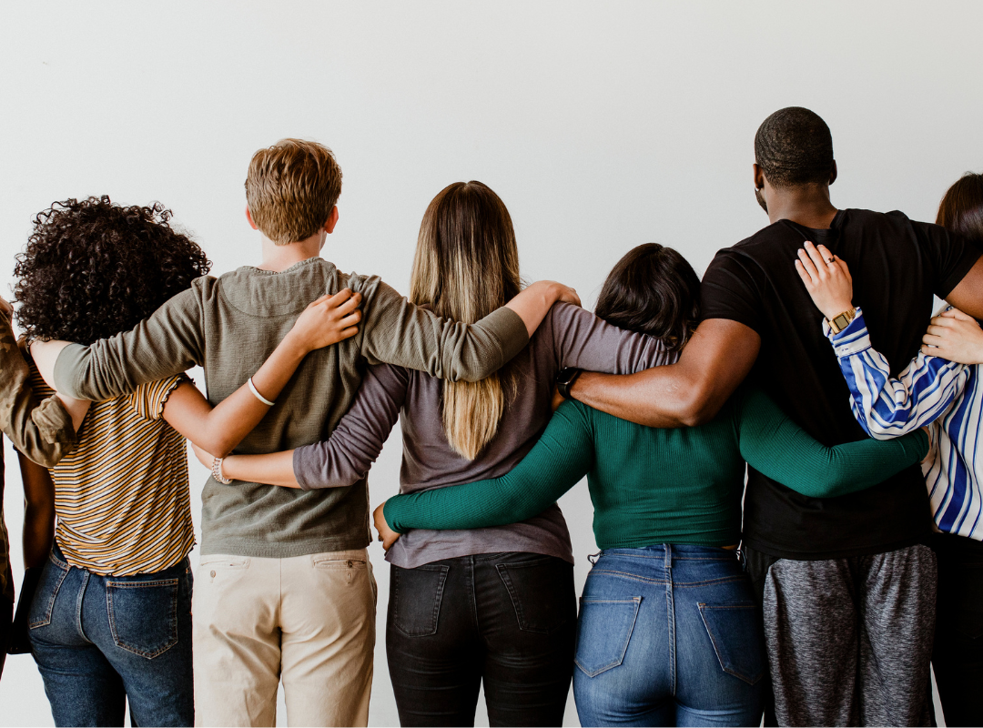 A group of diverse people seen from the back linking arms