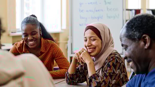 Three people talk and smile in front of a whiteboard