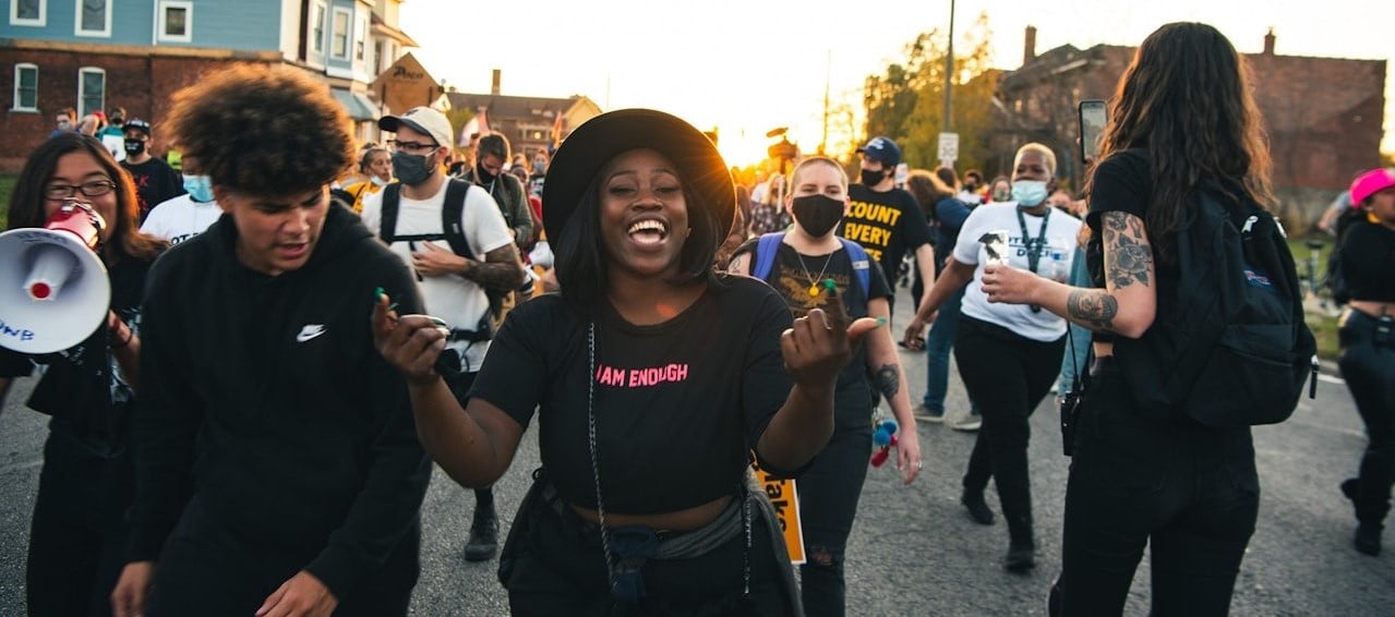 Photo of people marching at a protest with smiles on their faces