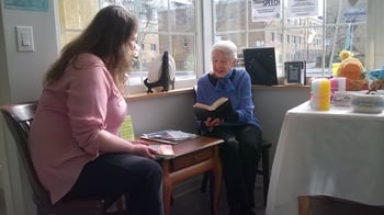 Woman sitting with woman reading