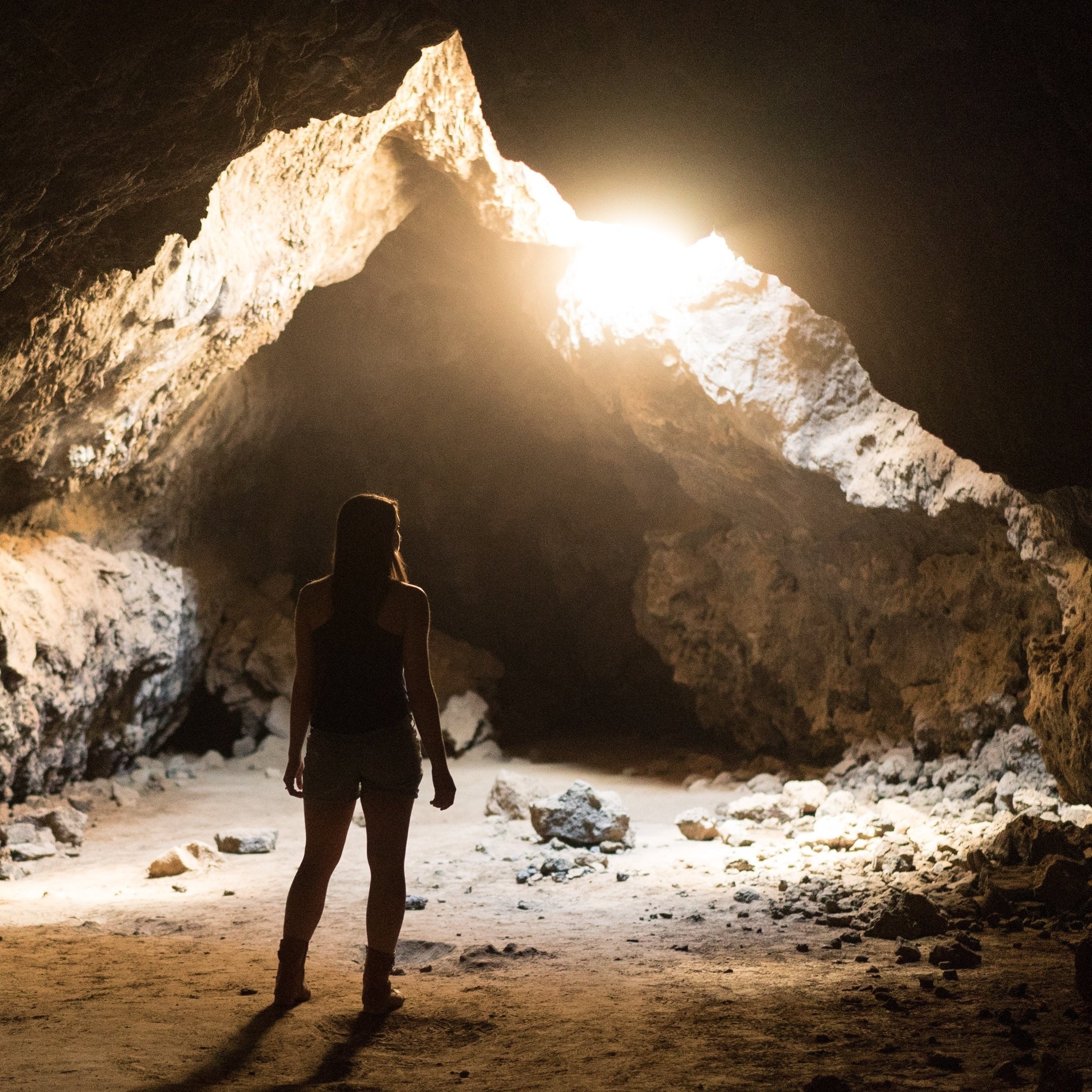 Woman standing in cave looking towards light