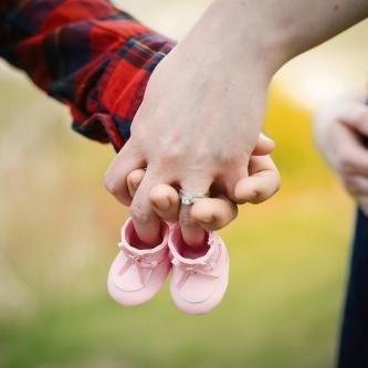 couple holding hands with baby shoe