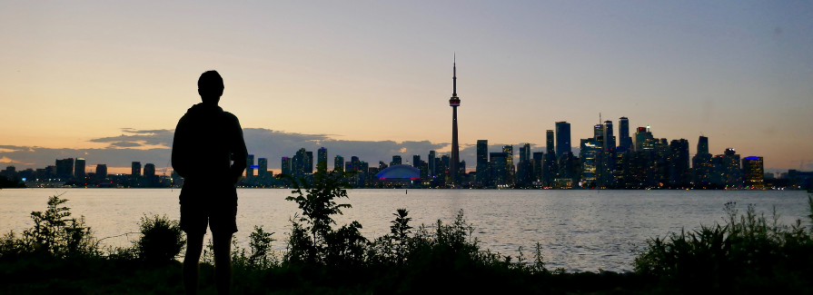 Silhouette of person looking at the Toronto skyline at dusk from Toronto Island.