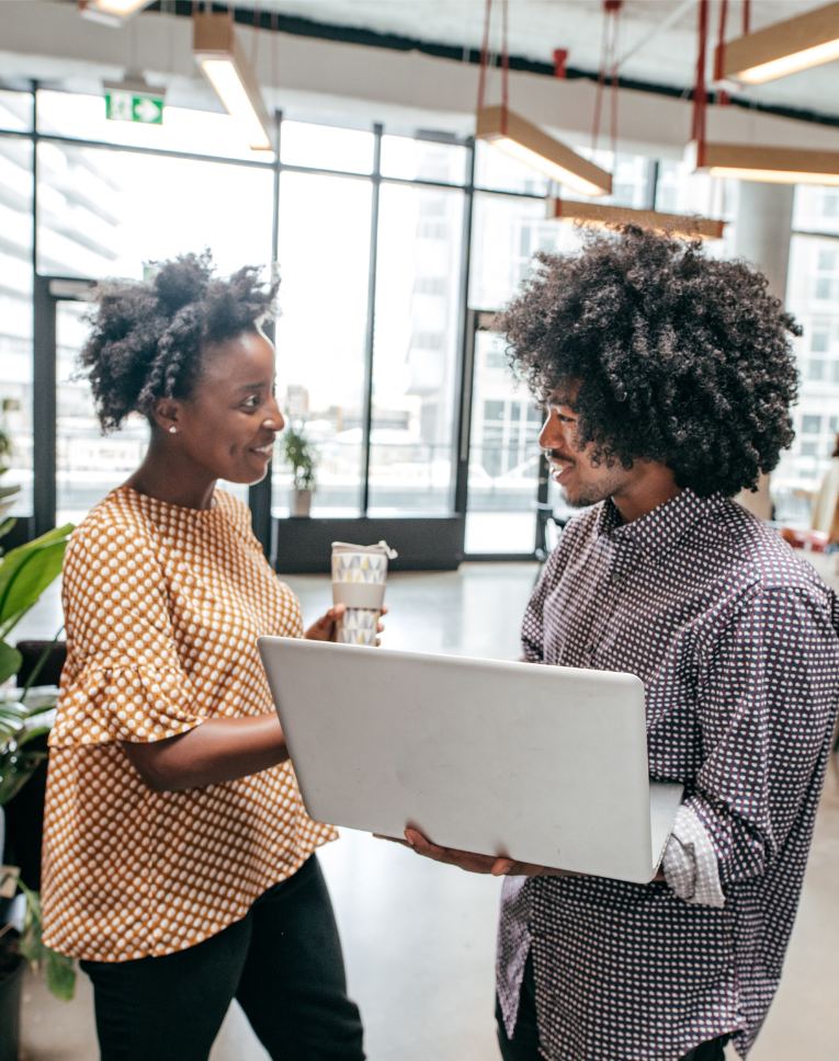 Two Black presenting people smiling and working together