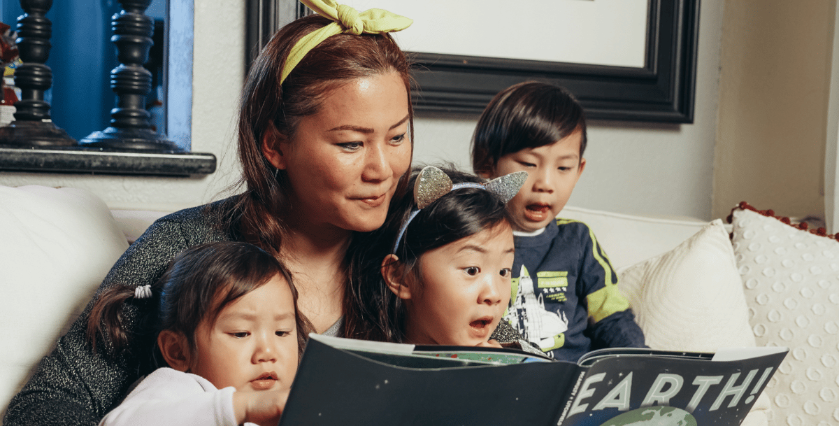 Woman reading to three young children