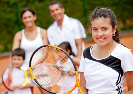Young female tennis player with her family at the background