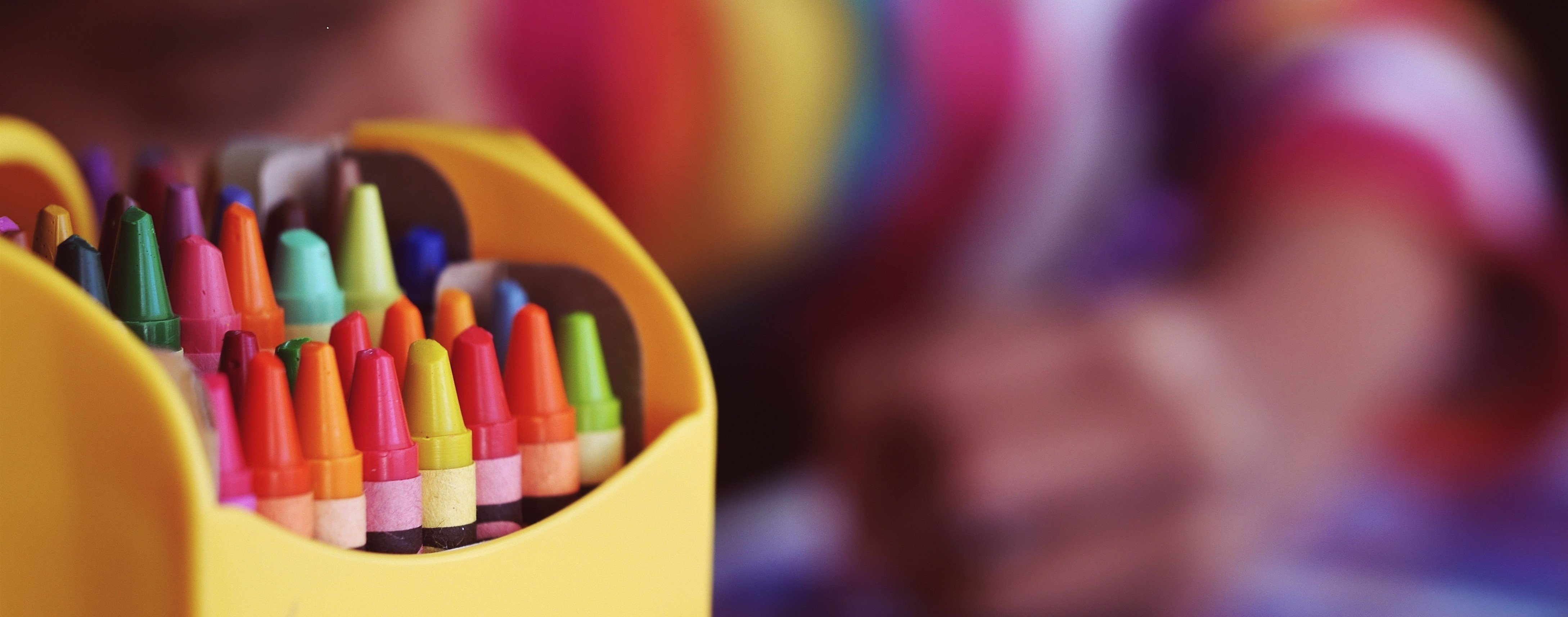 Child colouring with crayons in different colours.