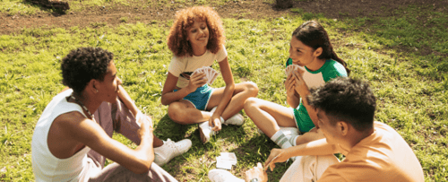 People sitting in the grass playing cards
