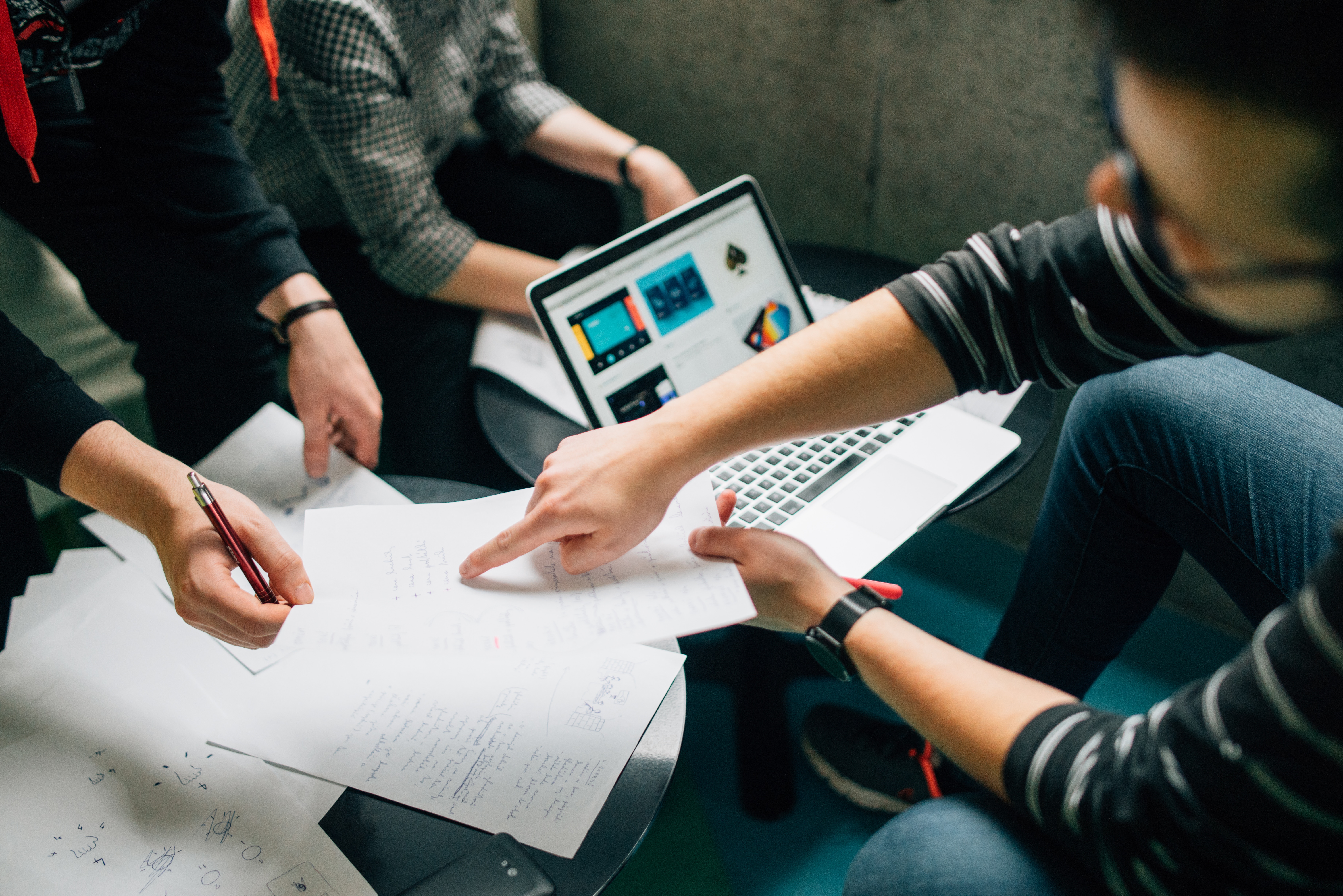 group of people brainstorming over laptop and paper