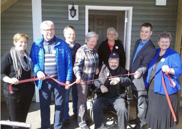 A group of people cutting a red ribbon

Description automatically generated