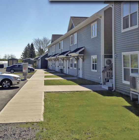 A row of apartments with a car parked in front

Description automatically generated
