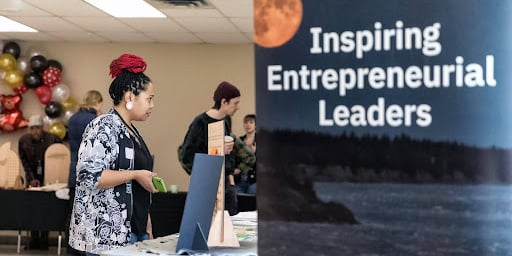 Several people observe information tables at an entrepreneur fair