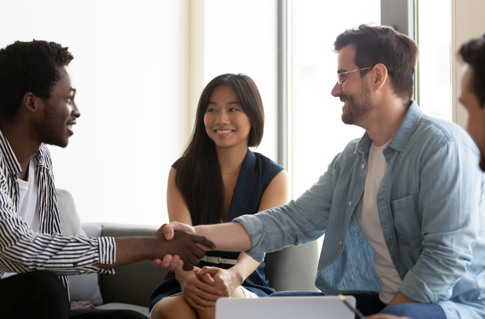 3 people shaking hands in a bright office setting