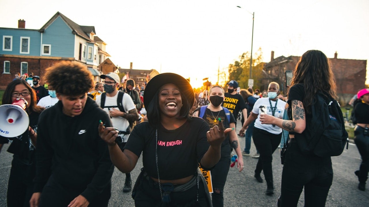 Photo of people marching at a protest with smiles on their faces