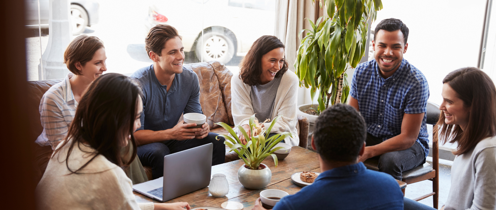 A group of people sit around a table chatting and smiling