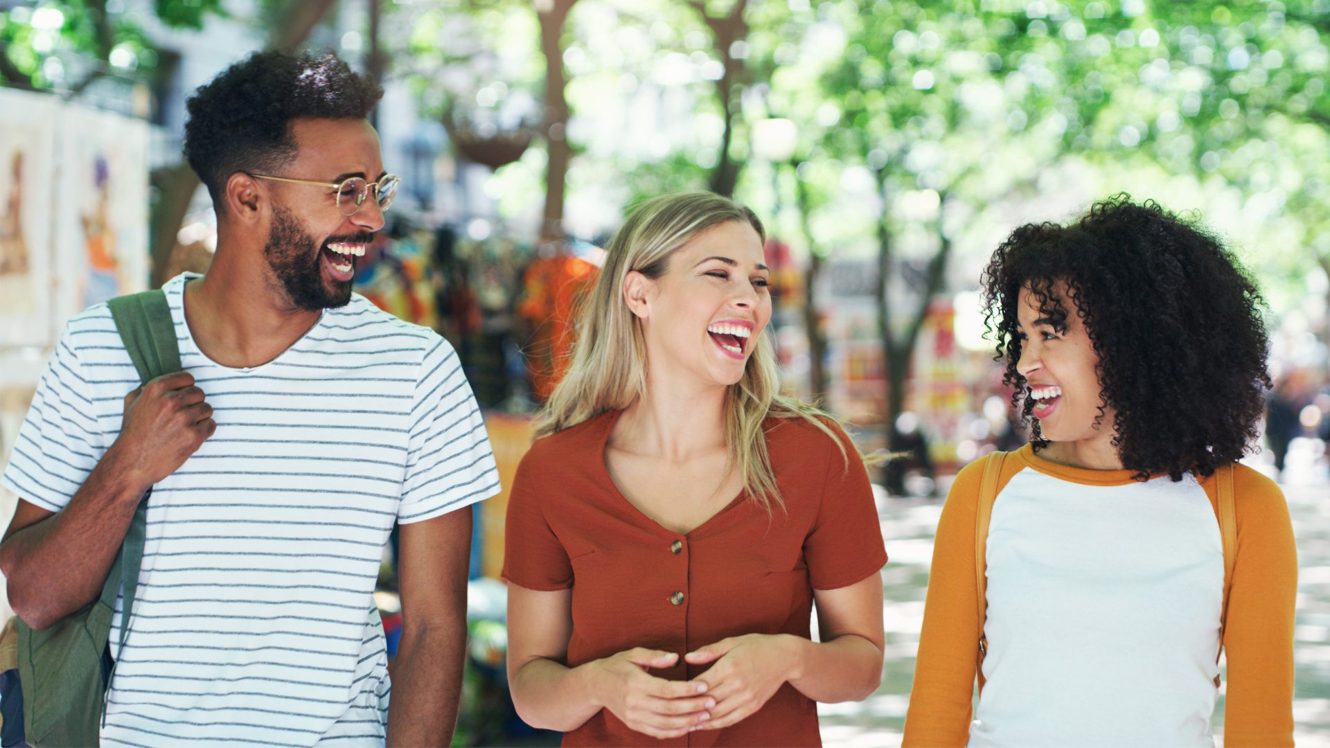 Three people walking and laughing together in a park